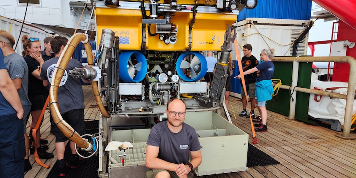Mehrere Wissenschaftler stehen vor und neben dem gelben ferngesteuerten Unterwasserfahrzeug Kiel 6000 an Deck des Forschungsschiffs Sonne.