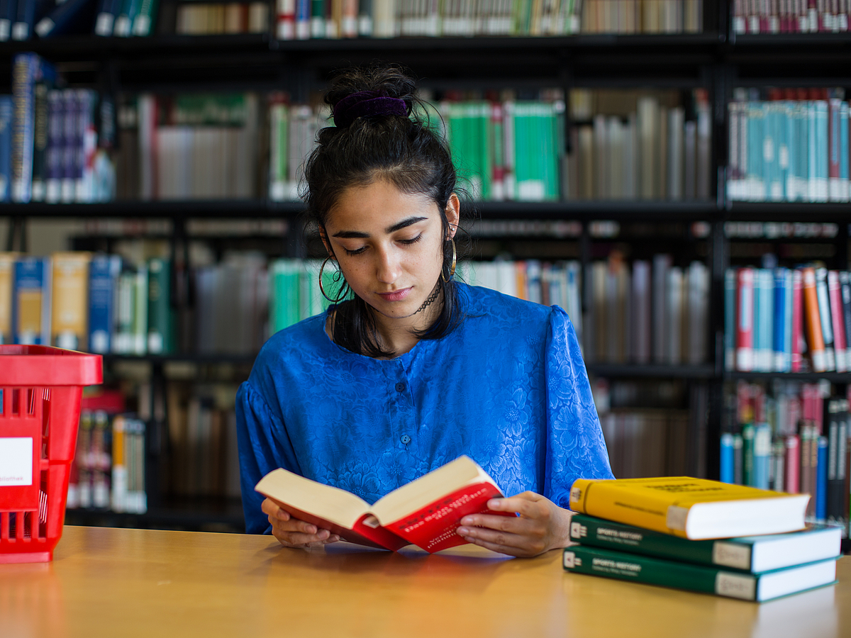 Eine Studierende beim Lesen in der Bibliothek.