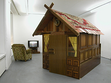 Filmstill: Holzhütte in einem Innenraum