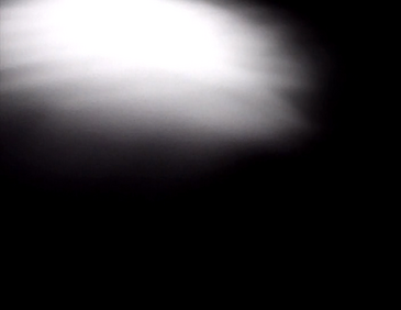 filmstill zeigt hellen Lichtfleck auf dunkler Fläche