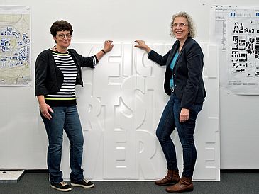 Zwei Frauen zeigen zwei Wandplatten