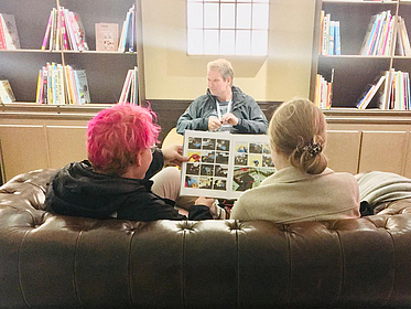 Zwei Studierende sitzen auf einem Sofa und lesen gemeinsam einen Comic