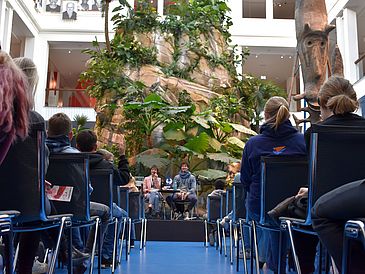 Froschperspektive auf das Podium mit Moderatorin und Autor
