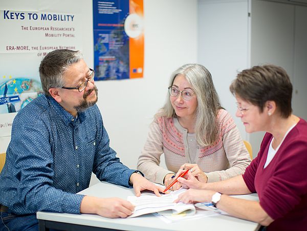 Three people in conversation at a table.