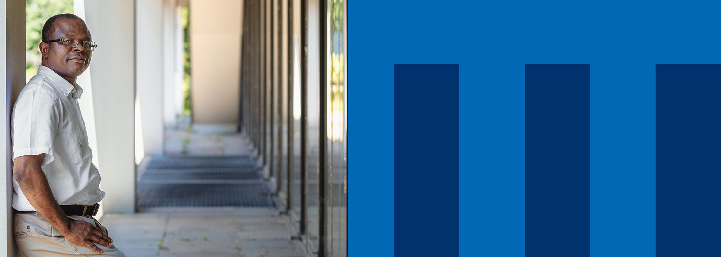 Kufre Okop steht in einer Galerie an eine Wand gelehnt und schaut in die Kamera.