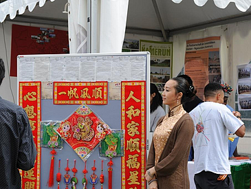 Chinesin in traditioneller Kleidung vor chinesischem Plakat.
