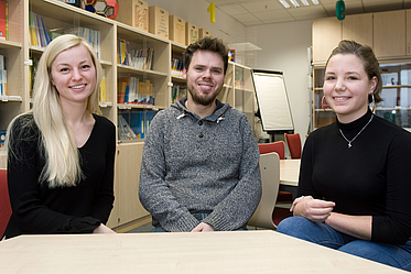 Drei Studierende lächeln in die Kamera