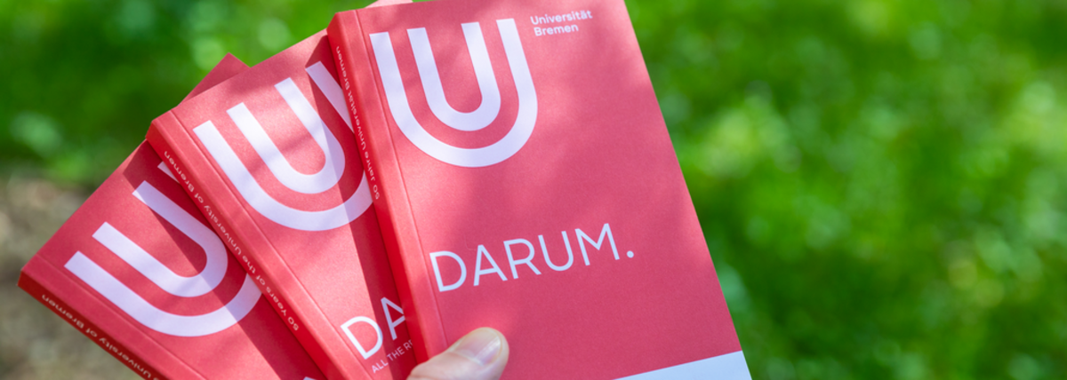 Eine Hand hält drei Magazine, auf dem Titel ist das Wort DARUM zu lesen
