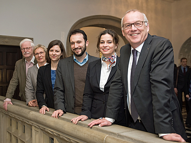 Sechs Personen lächeln in Kamera