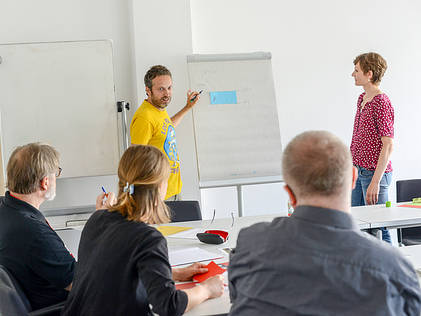 Two teachers working on a flipchart in front of an audience.
