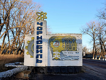 Zeigt eine Wand mit kyrillischen Schriftzeichen. Daneben eine Ölplattform. Neben der Ölplattform befindet sich das Zeichen der Sowjetunion.