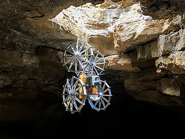 A robot rappels down a cave entrance