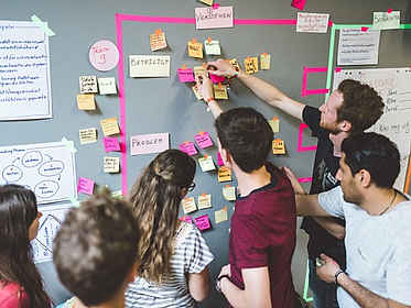 Menschen im Creativen Prozess vor einer Pinwand