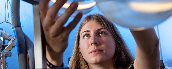 Eine Person hält einen Rundkolben aus Glas in der Hand.