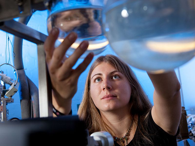 Eine Person hält einen Rundkolben aus Glas in der Hand.