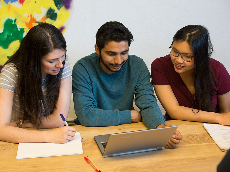 Young people work at a laptop.