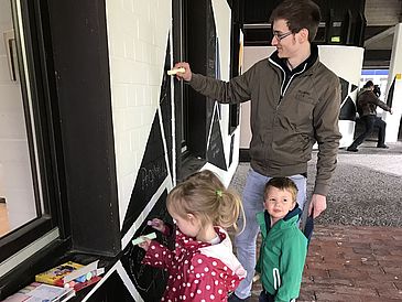 Kinder malen mit Kreide an einer Wand
