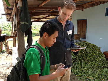 Zwei Männer testen die mobile4D-App auf Handy in Laos.