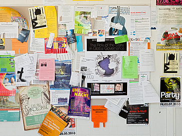 Schwarzes Brett voller Zettel.