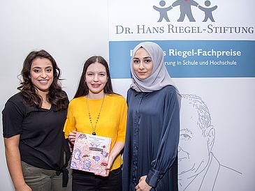 Drei junge Frauen zeigen ein Kinderbuch