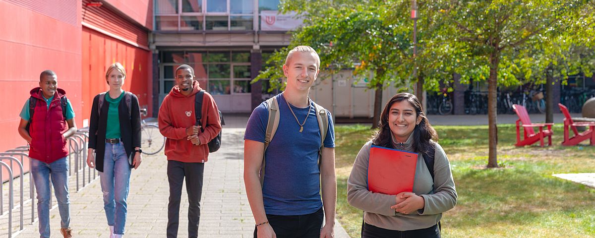 Studierende laufen am MZH entlang und unterhalten sich