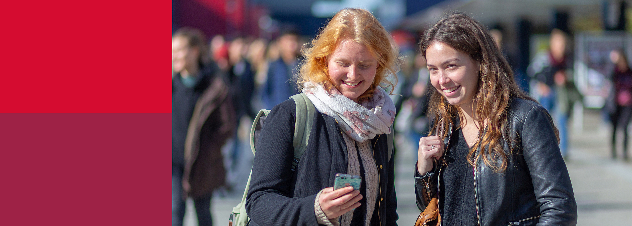 Zwei junge Frauen stehen auf dem Boulevard der Universität Bremen, eine schaut auf ihr Handy, als würde sie etwas suchen.