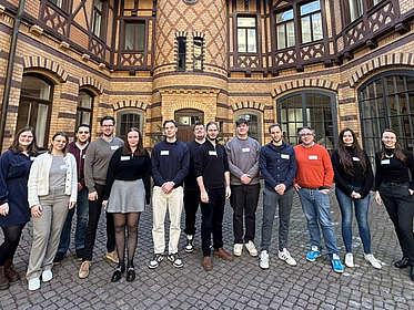 Gruppe von Studenten und Herr Decius sind umringt von einem alten Steingemäuer