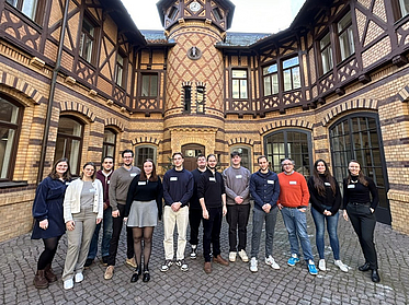 Group of students and Mr. Decius are surrounded by an old stone building