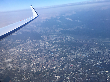 Luftaufnahme einer Stadt mit Flugzeugflügel im Vordergrund