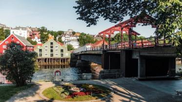 Ein Fluss hinter dem Häuser stehen. Auf der rechten Seite ist eine Brücke zum überqueren des Flusses.