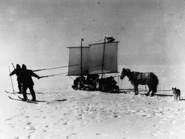 Menschen ziehen einen Schlitten durch den Schnee, dahinter ein Pferd