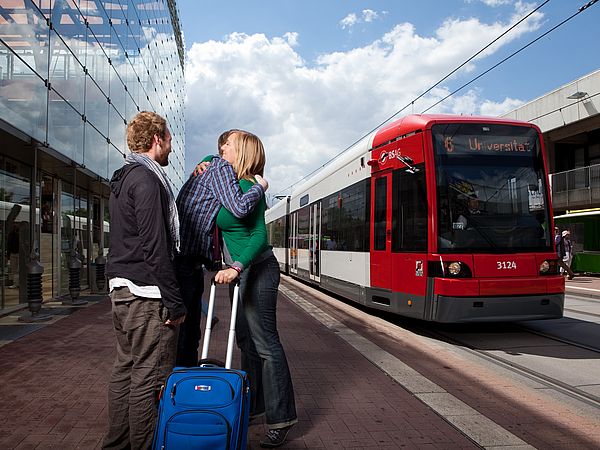 Studierende vor einer Straßenbahn an der Haltestelle Zentralbereich.