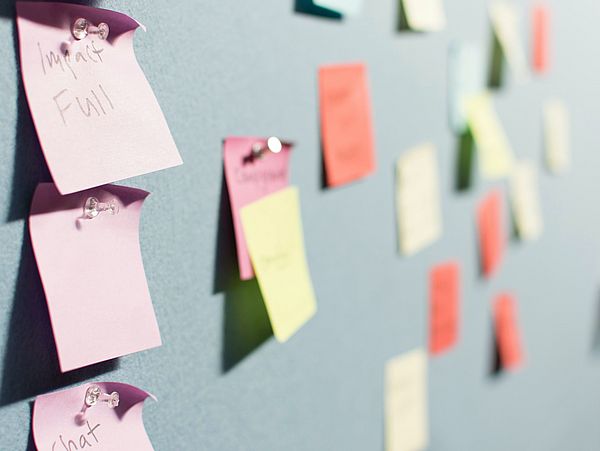 Eine blaue Pinnwand mit bunten Post-It's