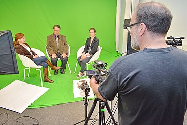 Mann mit Kamera dreht in einem Studio ein Interview