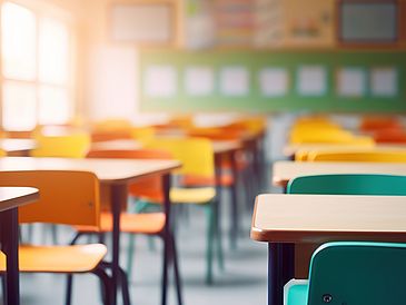 School classroom in blur background without young student. Blurry view of elementary class room no kid or teacher with chairs and tables in campus. Back to school concept.