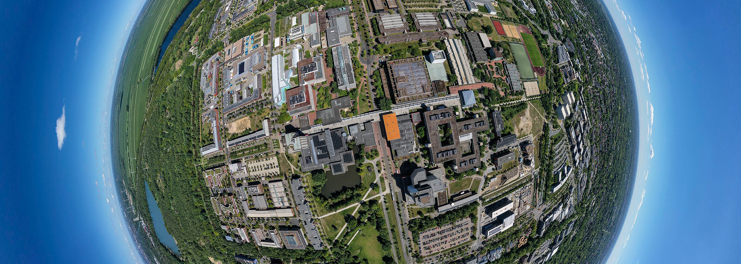 Mit einem Fischaugenobjektiv aufgenommenes Luftbild welches den Campus der Universität Bremen als von blauem Himmel umgebenen Globus erscheinen lässt.