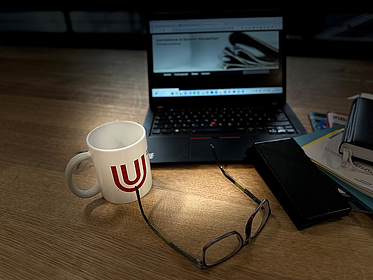 Holztisch mit Laptop, Kaffeetasse und Zeitschriften