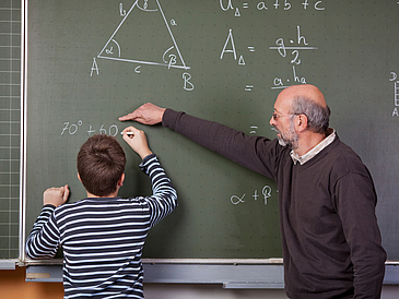 Mathelehrer mit Schüler an einer Tafel