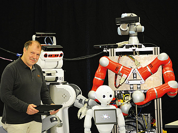 Mann mit drei humanoiden Robotern