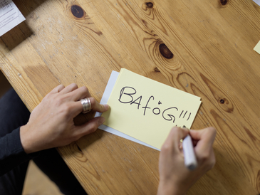 Eine Person schreibt das Wort BAföG auf ein Stück Papier