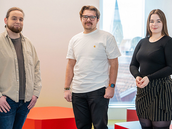 Die Studierenden Nils Kaufholz, Vincent Wagener und Emilia De Rosa posieren in der neuen Mensa am Domshof.