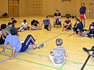 Sportler im Kreis, einer im Rollstuhl.