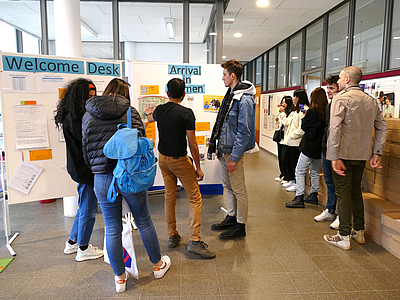 Studierende stehen an der Info-Tafel des Welcome Desk