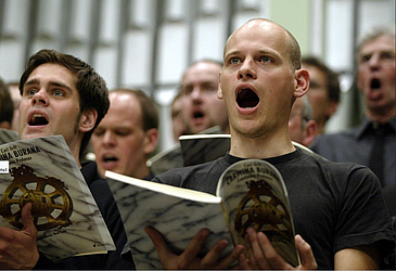 Singende Männer im Chor, sie halten Notenbücher in den Händen.