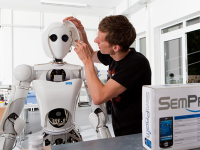 Eine Person arbeitet an einem humanoiden Roboter.