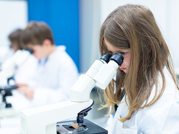 Mädchen blickt ins Mikroskop