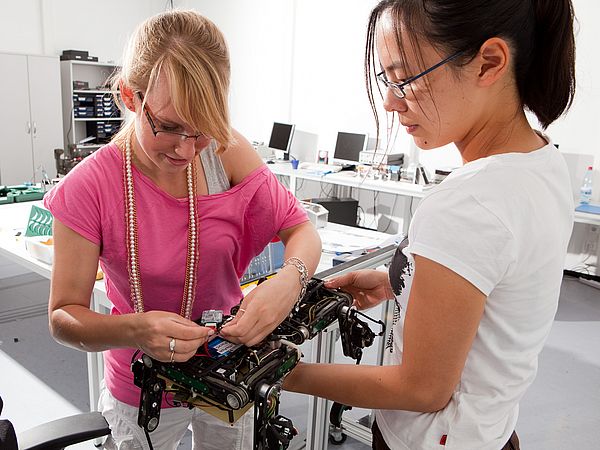 Zwei Personen arbeiten in einem Labor an einem Roboter.
