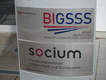 Schilder mit der Aufschrift SOCIUM und BIGSSS an Eingangstür