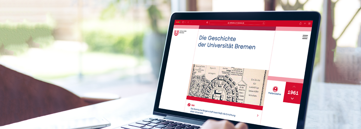 Auf einem Tisch steht ein aufgeklappter Laptop. Darauf ist eine Webseite zu sehen, die mit "Die Geschichte der Universität Bremen" überschrieben ist