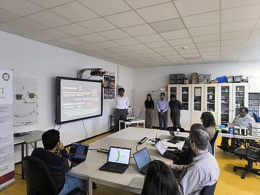 Vier StudentInnen halten einen Vortrag im Labor der AG ComNets